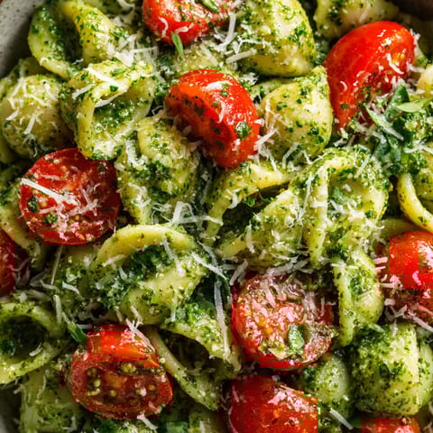 A bowl of pasta with tomatoes and basil.