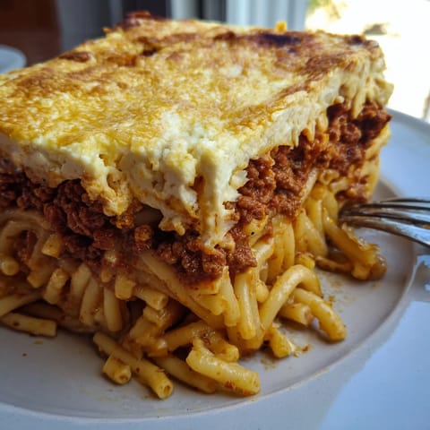 Golden-brown Greek Pastitsio casserole, filled with pasta, spiced beef, and rich sauce.  