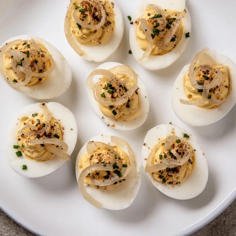Savory Everything-Spiced Deviled Eggs with Pickled Shallots showcase creamy filling under a sprinkle of seasoning.