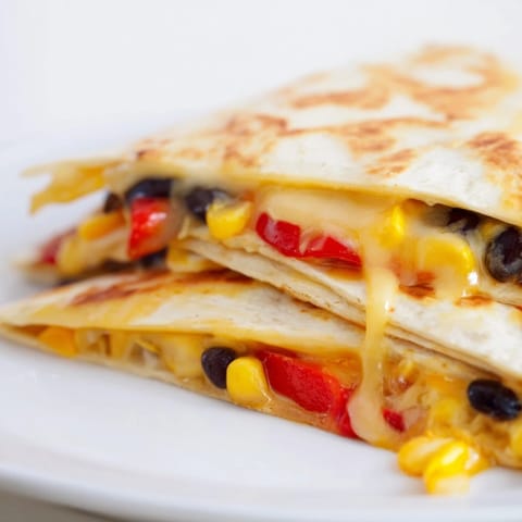 A close-up of a warm, cheesy tortilla wrap hack with black beans, ready to eat.