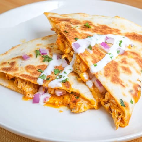 A close-up of a perfectly grilled buffalo chicken quesadilla, ready to serve with ranch dressing.