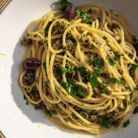 Bright image of Olive Tapenade Pasta, glistening with olive oil and fresh herbs, ready to serve.