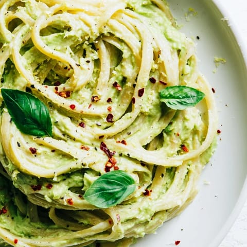 Vibrant green Smashed Avocado Pasta, a quick vegetarian meal ready to eat, served on a plate.