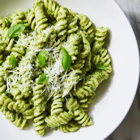 A visually appealing bowl of Creamy Sunflower Seed Pesto Pasta, garnished with fresh basil leaves.