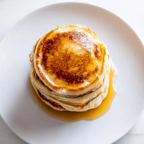 Golden-brown Protein Power Pancakes cooking on a griddle, bubbling and ready to flip.