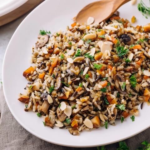 Warm Wild Rice and Mushroom Pilaf served in a rustic bowl, topped with crunchy toasted almonds and fresh thyme.