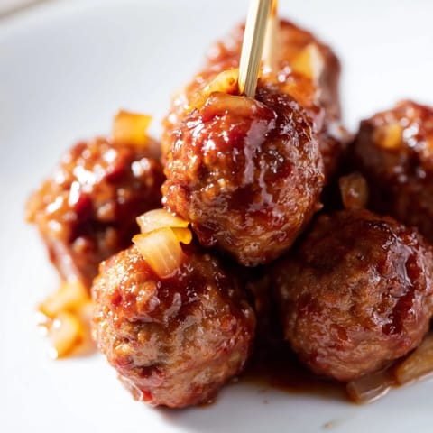 Tender beef meatballs simmered in a tangy peach preserve and chili sauce, served hot with toothpicks for gatherings.  