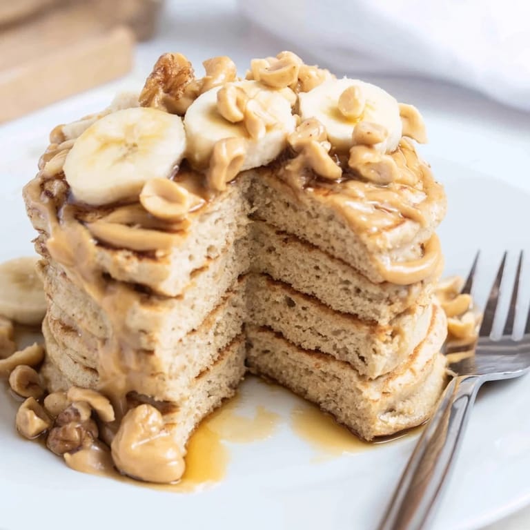 Indulge in Peanut Butter Maple Oat Pancakes garnished with chopped peanuts and syrup.