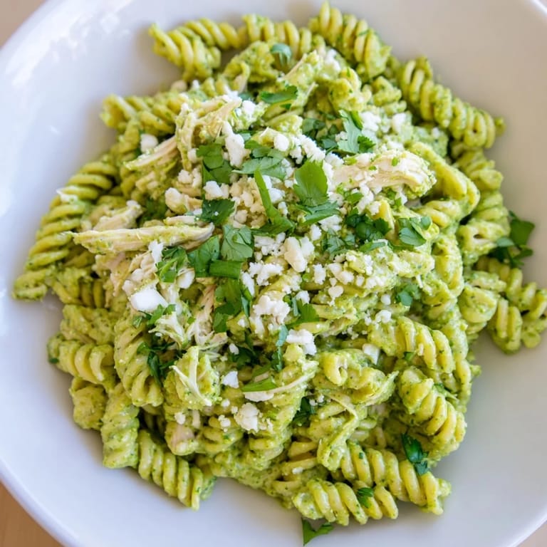 Tender shredded chicken and pasta coated in a zesty cilantro lime sauce, ready to serve and enjoy.