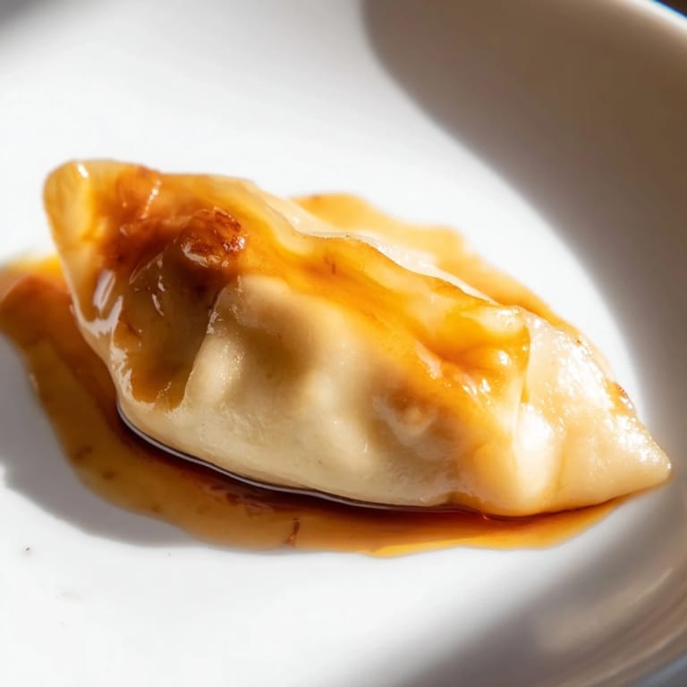 Eight Chīzu Imomochi snacks arranged on a white ceramic platter, featuring soft, boiled potato dumplings with melted cheese centers, lightly pan-fried and coated in a glossy, savory-sweet sauce, ready to be enjoyed as a comforting appetizer.  