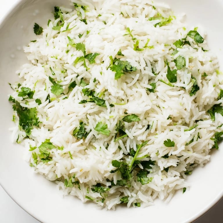 Steamed white rice tossed with vibrant cilantro and fresh lime juice, served warm in a ceramic bowl for a Mexican-inspired side dish.