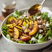 A bowl of salad with peaches and blue cheese.