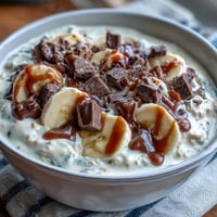 Creamy overnight oats topped with fresh banana slices and rich dark chocolate chunks for a wholesome breakfast treat.